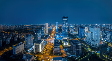 Fototapeta premium Modern city commercial financial district skyline with illuminated skyscrapers at night in Suzhou.