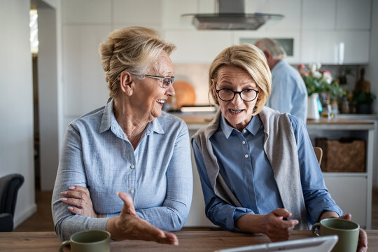 Senior women talking and discussing content on digital tablet