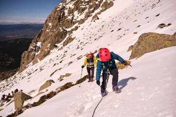 Family with mountaineering equipment carrying their son roped up down a snowy slope