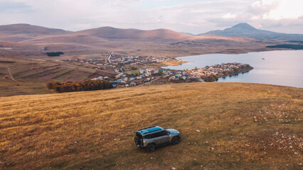 Off-Road Vehicle Overlooking a Serene Mountain Lake and Village
