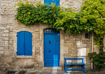 Beautiful typical house front with blue door and blue shutters in the historic old town of Arles,...