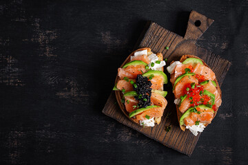 Avocado and salmon appetizer on the Christmas table. Canapes with fish and caviar. Top view