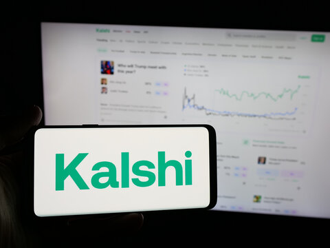 Stuttgart, Germany - 10-27-2025: Person holding smartphone with logo of US prediction market company Kalshi Inc. on screen in front of website. Focus on phone display.