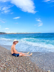 Young man doing stretching exercises on pebble beach with Mediterranean Sea waves in Antalya, Turkey. High quality photograph