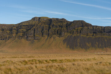 Majestic mountain with a textured slope in a expansive grassland area.