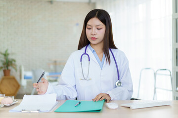 Asian female doctor working on medical report documents.