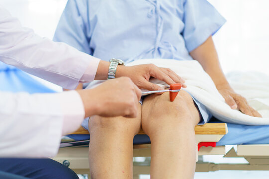 Doctor checking elderly patient’s knee for osteoarthritis.