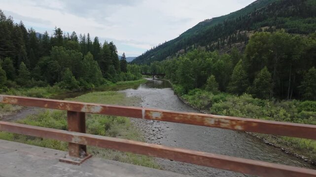 Slow Motion View of River and Train Trestle from Moving Car in Montana