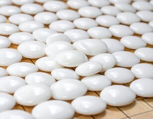 Close-up of numerous, glossy white stones arranged randomly on a wooden, grid-patterned surface. The stones are round