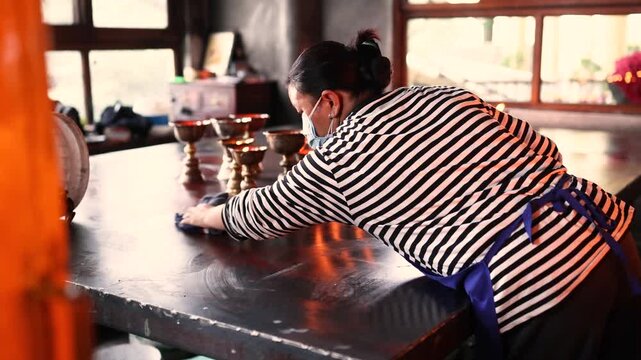 Woman in striped long sleeve shirt cleaning candle stand indoors