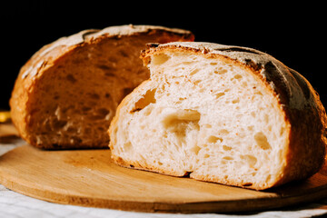 Freshly baked artisan bread cut open on a wooden board in a warm kitchen setting
