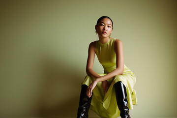 Asian woman sitting with a confident expression in chartreuse dress  