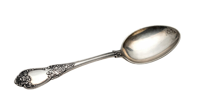 Ornate silverware teaspoon lays diagonally against a stark black background. Patina hints to age and use