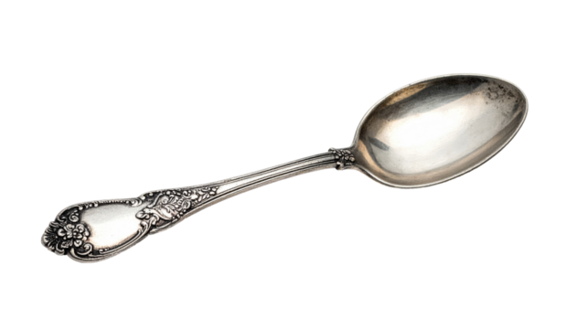 Ornate silverware teaspoon lays diagonally against a stark black background. Patina hints to age and use