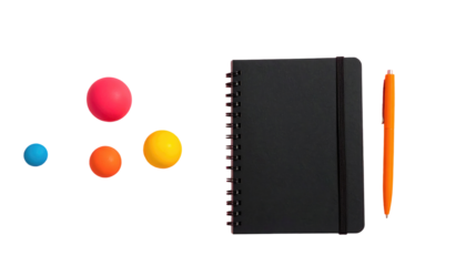 Flat lay Four balls, a black notebook with band, and an orange pen arranged on a black background