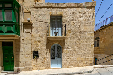 Fototapeta premium A typical house front in Birgu, Malta - with white door and green door, and a traditional green balcony