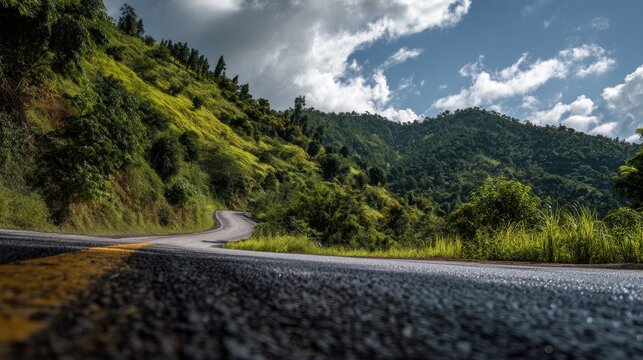 Bumpy asphalt road curving up a green hill in Lampang, Thailand, with tropical vegetation and clear sky.