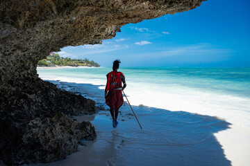 A Masai man walks along a beautiful Indian Ocean beach.