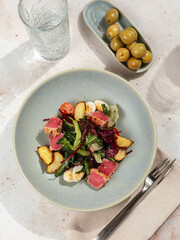 Asian style tuna salad with lettuce, eggs, cherry tomatoes potato and tuna pieces in sesame seeds. Healthy dinner. Vertical. Copy space. Top view or flat lay.