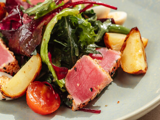 Asian style tuna salad with lettuce, eggs, cherry tomatoes potato and tuna pieces in sesame seeds. Healthy tuna salad. Close up.