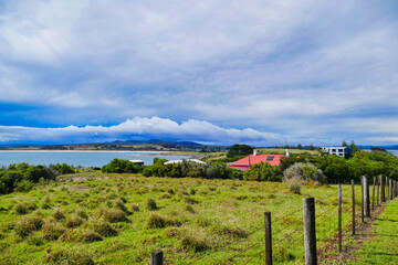 View from Low Head, George Town, in the Launceston region of Tasmania, Australia. Meadow and rural fence in the foreground. Sky with dark rainclouds.
