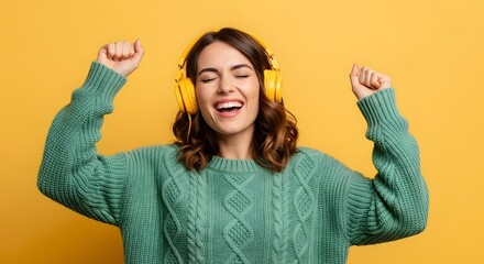 Joyful young woman dancing and singing while wearing headphones and a cozy sweater