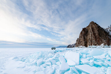 Blue ice with snow on Baikal lake at sunrise. Khoboy cape of Olkhon island, Baikal, Siberia, Russia