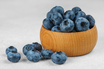 Fresh ripe blueberries in small wooden bowl on gray textured stone background. Delicious organic fruit rich in vitamins, wild berries,healthy lifestyle, natural food. Close up, macro