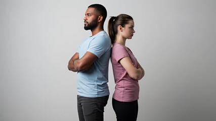 Diverse couple standing back to back in silent disagreement, showcasing relationship tension and conflict, ideal for illustrating communication breakdowns and emotional barriers