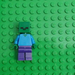 Naklejka premium A Lego Minecraft Zombie minifigure, a popular character from the video game, stands on a green Lego baseplate