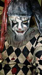 A man dressed as an evil jester or clown, with different colored contact lenses, covered in blood...