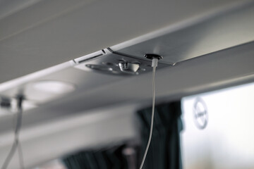 A close-up shows a white charging cable plugged into a black USB port located in the overhead panel...
