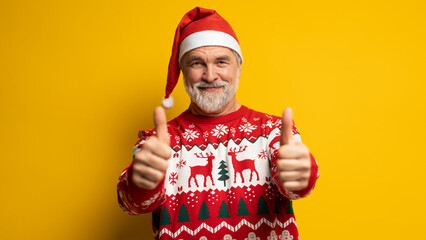 Merry satisfied smiling mature man wear knitted christmas sweater Santa hat posing showing thumb up...