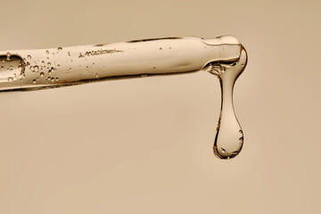 Serum in a pipette close-up on a beige background.