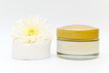 White glass container with white cotton pads flowers on white background.