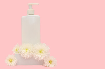 White container with dispenser on pink background with white flowers.