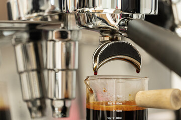 Coffee machine brewing espresso in to glass cup.Barista while preparing and working with coffee machine and making espresso coffee from arabica coffee beans.