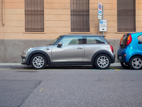 Urban parking scene featuring silver Mini Cooper beside blue electric car, showcasing modern transportation and eco friendly vehicle trends