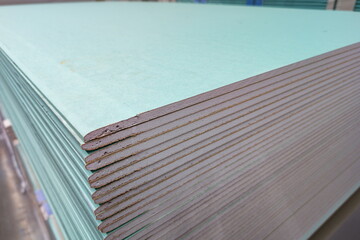 Stacked sheets of light green construction material in a warehouse ready for use in building projects