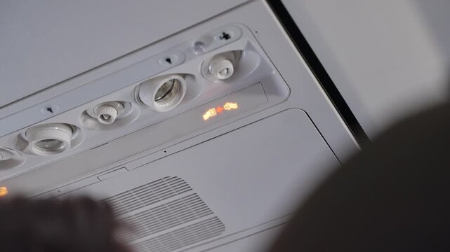 Fasten seatbelt sign is turned on during airplane flight to warn passengers. Overhead alert or caution sign or signal to put on seatbelts on plane is lit while onboard. Turbulence or landing procedure