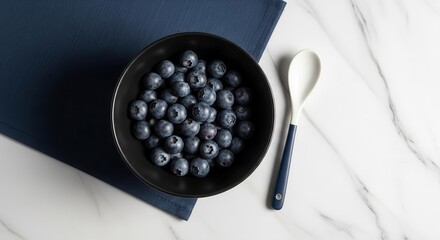 Fresh Blueberries In Elegant Black Bowl With Spoon On a Stylish Marble Surface