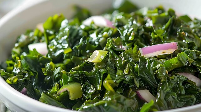 Close up of a white bowl filled with fresh green kale and sliced red onions ready to be served - Powered by Adobe