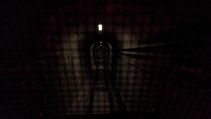 Dark Tunnel with Railway Tracks and Distant Light