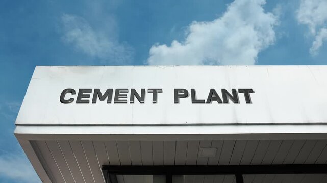 Cement Plant word sign boldly displayed on the massive, industrial exterior of a factory complex beneath a clear blue sky, signifying a large-scale manufacturing facility for producing cement for cons