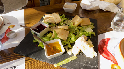 Cheese Platter with Honey, Jam, and Fresh Greens on Slate Board