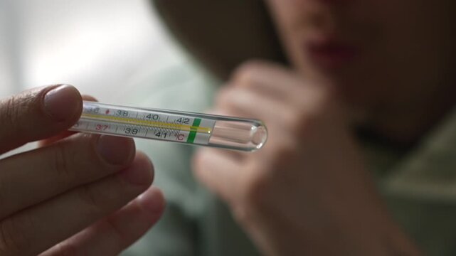 Measuring body temperature during colds and flu.
A sick person with bronchitis measures their body temperature.
Viral infection and poor health in a person.
Close-up of a mercury thermometer.