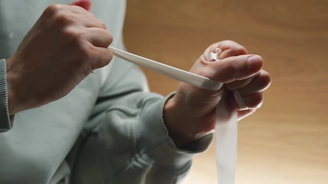 A man pulls on a rope, trying to damage and tear it.
A long, torn white ribbon.
Satin, tearing, tugging, pulling