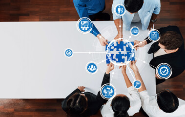 A diverse team engages in collaborative management as they work together on a global puzzle piece graphic, symbolizing teamwork, innovation, and strategic success in business. Amity