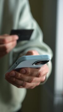 Money transfer from a bank card.
Transferring money to an e-wallet.
Topping up a mobile phone account and paying utility bills.
A person holding a phone and a credit card.