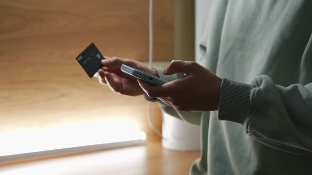 Money transfer from a bank card.
Transferring money to an e-wallet.
Topping up a mobile phone account and paying utility bills.
A person holding a phone and a credit card.